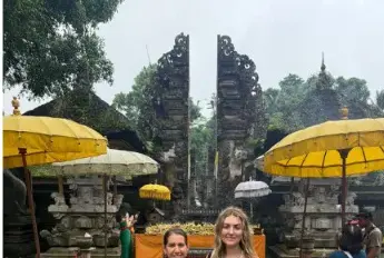 Guests at a Balinese temple gate with ceremonial umbrellas